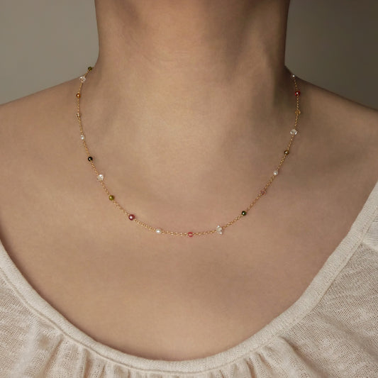 Lenora dainty high quality multi-colored gemstone beaded chain adjustable necklace 14K gold filled, show worn on a person's neck. Featuring high quality AAA Herkimer Diamond Quartz, Garnet, Rainbow Tourmaline, Natural Freshwater Rice Pearls and Smokey Quartz gemstones.