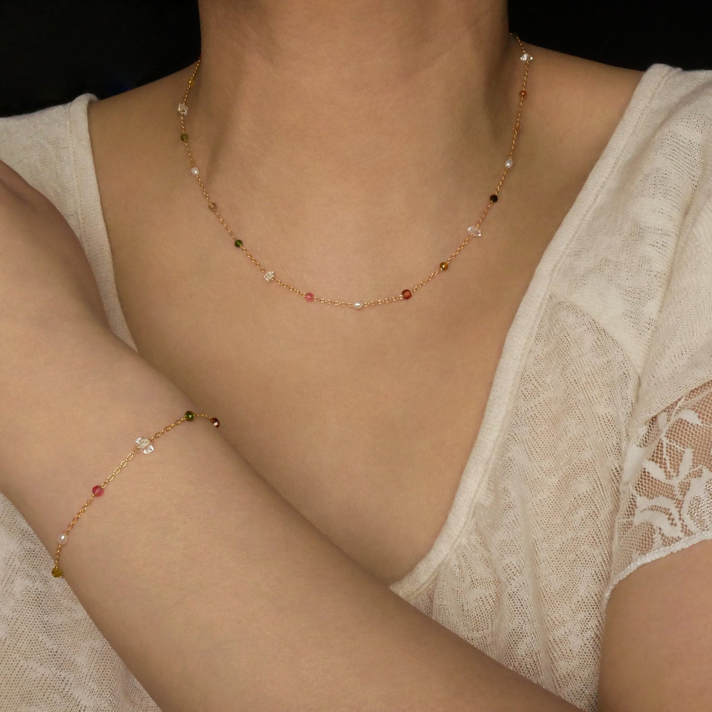 Lenora dainty high quality multi-colored gemstone beaded chain adjustable necklace and bracelet in 14K gold fill, show worn on a model's neck and wrist. Featuring high quality AAA Herkimer Diamond Quartz, Garnet, Rainbow Tourmaline, Natural Freshwater Rice Pearls and Smokey Quartz gemstones.