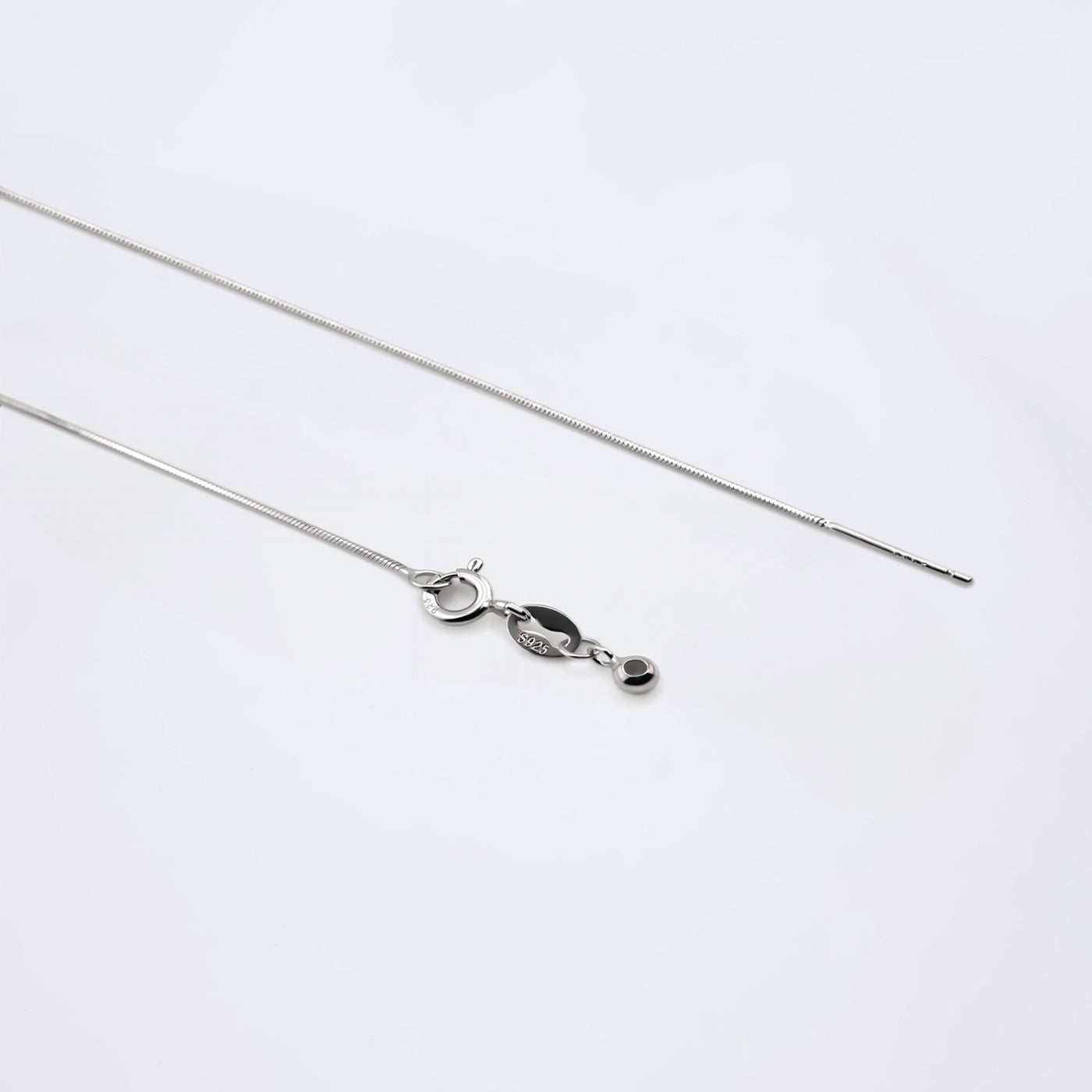 Dainty adjustable sterling silver snake chain necklace. It shows the ends of the adjustable pin, ball and clasp laying flat on a plain white background.