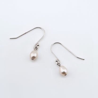 Pearl drop French hook earrings on plain white background, top view.