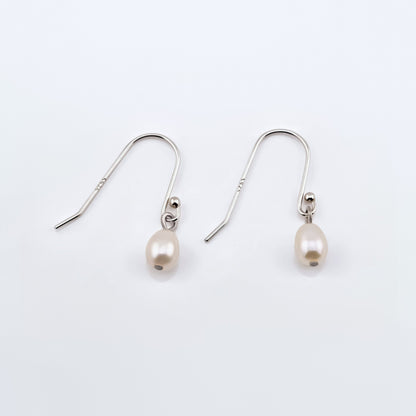 Pair of Pearl drop French hook sterling silver earrings on a plain white background, top view.