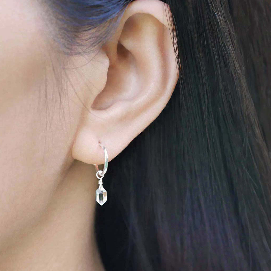 Dainty high quality Herkimer Diamond Quartz drop on Sterling Silver hoop earring worn by a person with long, dark hair.