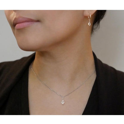 Pair of dainty high quality Herkimer Diamond Quartz drops on Sterling Silver hoop earrings and a dainty Herkimer Diamond Quartz drop pendant necklace, worn by a person with their hair up and wearing a black top.