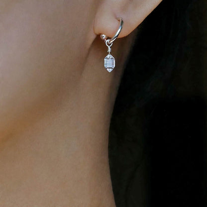 Close up of dainty, high quality Herkimer Diamond Quartz drop on Sterling Silver hoop earring, worn by a person with long, dark hair.