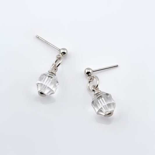 A pair of sterling silver clear quartz crystal prism earrings laying flat on a white background, top view.