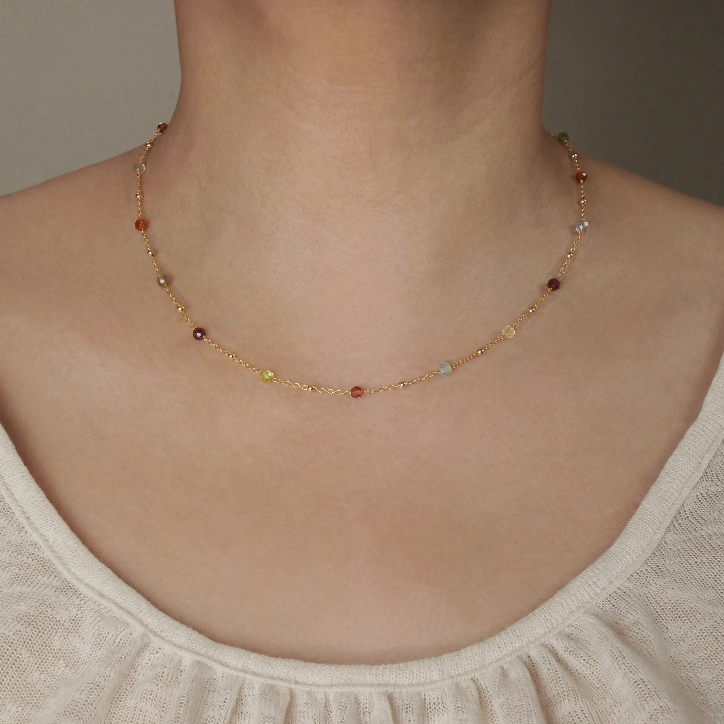 Estelle dainty high quality natural multi-colored gemstone beaded chain adjustable necklace 14K gold filled, shown worn on a person's neck. Featuring high quality AAA Apatite, Agate, Citrine, Garnet, Labradorite, Obsidian, Peridot gemstones.