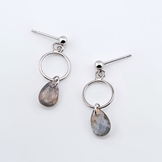 A pair of sterling silver, open circle labradorite drop earrings laying flat on a plain white background, top view.