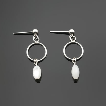 A pair of sterling silver, open circle mother of pearl MOP drop earrings laying flat on a plain dark gray background, top view.