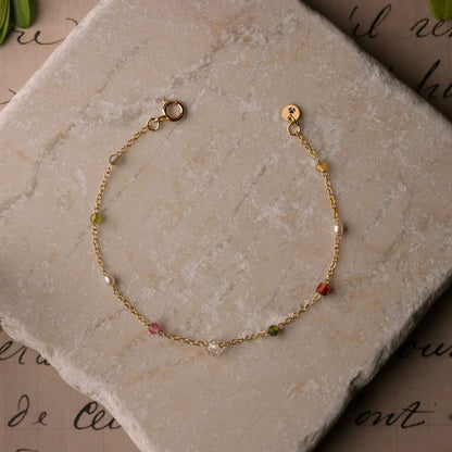 Lenora high quality natural multi-colored gemstone beaded chain bracelet 14K gold filled, top view on a stone background.