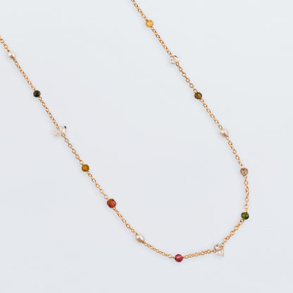Close up of Lenora high quality natural multi-colored gemstone beaded chain adjustable necklace 14K gold filled, top view with plain white background. Featuring high quality AAA Herkimer Diamond Quartz, Garnet, Rainbow Tourmaline, Natural Freshwater Rice Pearls and Smokey Quartz gemstones.