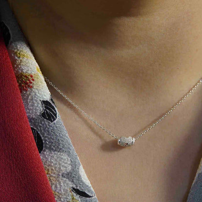 Dainty adjustable chain sterling silver textured sparkly barrel pendant necklace worn by a person wearing a beautiful Japanese Kimono in red with black, gray and white floral pattern.