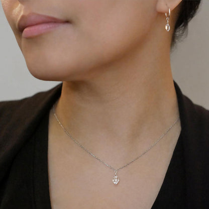 Close-up of a person wearing a dainty high quality AAA Herkimer Diamond Quartz wire wrapped pendant chain necklace and matching Herkimer earring hoops in sterling silver. The person has on a black top and sweater.