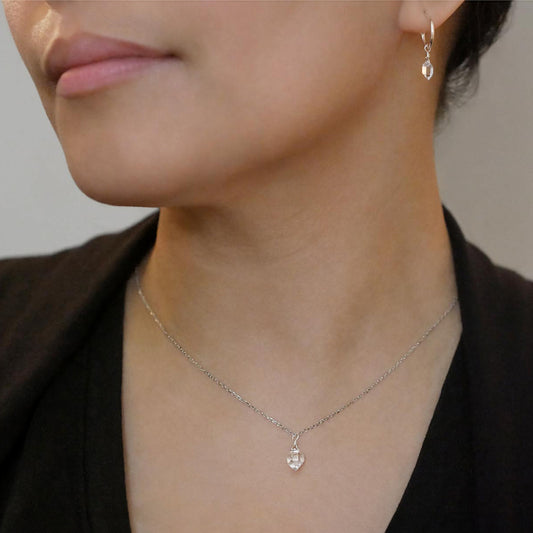Close-up of a person wearing a dainty high quality AAA Herkimer Diamond Quartz wire wrapped pendant chain necklace and matching Herkimer earring hoops in sterling silver. The person has on a black top and sweater.
