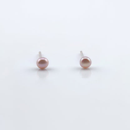 Front view of a pair of dainty natural pink pearl stud earrings on plain white background.