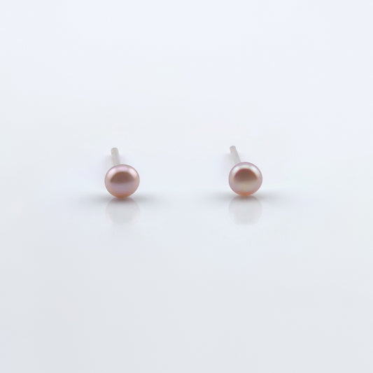 Front view of a pair of dainty natural pink pearl stud earrings on plain white background.