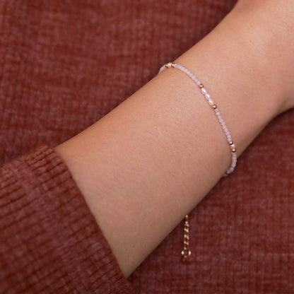 Close-up of a wrist wearing dainty  smooth amazonite beads and accent rice pearls high quality AAA beaded bracelet, with 14K gold filled accent beads. The background is a person wearing a brown long sleeve sweater.