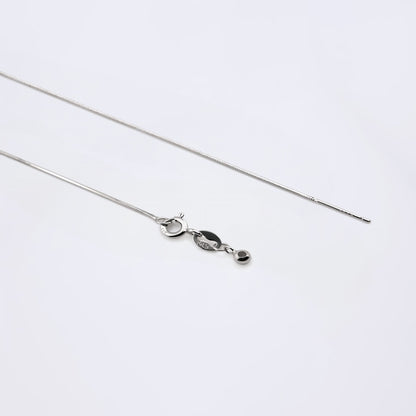 Dainty adjustable sterling silver snake chain necklace. It shows the ends of the adjustable pin, ball and clasp laying flat on a plain white background.